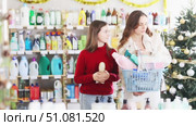 Cheerful teenage girl with mother shopping for home essentials and personal care products in festively decorated store in Christmas season. Стоковое видео, видеограф Яков Филимонов / Фотобанк Лори