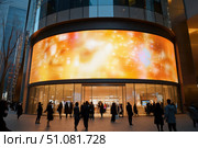 A huge curved LED screen dominates the entrance of a flagship store at an upscale mall. This technological marvel enhances the shopping experience with its dynamic and immersive display. Стоковое AI-изображение, AI-художник Nart / Фотобанк Лори