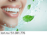 A radiant female smile shines with gleaming white teeth, surrounded by a swirl of blue water and mint leaves. This artistic scene embodies freshness and impeccable oral hygiene. Стоковое AI-изображение, AI-художник Nart / Фотобанк Лори