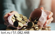 A person holds a broken pink piggy bank with coins spilling out. The scene represents financial struggles and savings management. Стоковое AI-видео, аниматор Nart / Фотобанк Лори