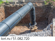 Large diameter plastic pipe for water supply. A smooth black plastic pipe with a blue stripe is placed in the trench. Installation of water supply systems. The excavation where the pipes are connected. Стоковое фото, фотограф Эдуард Белкин / Фотобанк Лори