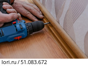 A male repairman installs baseboards at home. Room renovation... Стоковое фото, фотограф lyudmila Soloveva / Фотобанк Лори