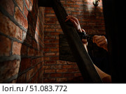 BDSM Close-up of hands in handcuffs. The man dominates and rivets his mistress to the Andreev cross. Games for adults. Brick wall. Red room. Стоковое фото, фотограф Михаил Решетников / Фотобанк Лори