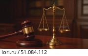 A wooden gavel and a brass scale of justice on a polished wooden table. The setting suggests a courtroom or legal environment. Стоковое AI-видео, аниматор Nart / Фотобанк Лори