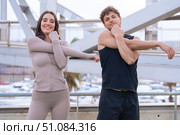 Fit couple stretching arms outdoors before workout on urban bridge. Стоковое фото, фотограф Raquel Corcoles Mendez / Фотобанк Лори