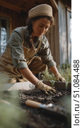 Gardener tending to seedlings in rustic greenhouse with natural lighting and greenery present. Стоковое AI-видео, аниматор Сергей Толмачёв / Фотобанк Лори