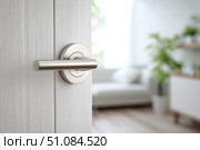 Doorknob. Metal door handle lock and latch of brass on veneer doors. Door wooden half opening through interior bedroom background, selective focus. Modern trends in interior design. Close-up. Стоковое AI-изображение, AI-художник Марина Демидюк / Фотобанк Лори