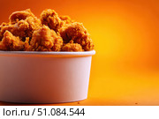 Crispy chicken on a yellow orange color background. Bucket overflowing with golden Fried Chicken Strips. Street food. Coated batter southern style chicken drumsticks and pieces. BBQ Feast. Nuggets. Стоковое AI-изображение, AI-художник Марина Демидюк / Фотобанк Лори