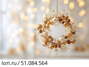 Delicate wreath of golden Christmas decorations hangs on the white wall. Magic and joy festive celebrations during the winter season. Elegant gold and silver Ornaments beautifully decorated setting. Стоковое AI-изображение, AI-художник Марина Демидюк / Фотобанк Лори