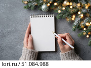 Woman's hand writing in empty notebook at the desk with Christmas decoration. Back to life, goal list. Plan, goals, checklist, idea concept. Top view, copy space. New Year. Blank White Paper Sheet. Стоковое AI-изображение, AI-художник Марина Демидюк / Фотобанк Лори