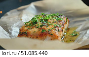 Grilled salmon fillet garnished with herbs on parchment paper. The dish is presented with a drizzle of olive oil, showcasing a delicious meal. Стоковое AI-видео, аниматор Nart / Фотобанк Лори