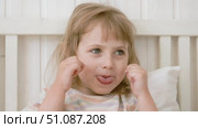4 years girl joking, sticking tongue out with silly expression. Child making face. Funny foolishness portrait of little kid doing crazy comical gesture among a white wall. Closeup face. Low contrast. Стоковое видео, видеограф Марина Демидюк / Фотобанк Лори