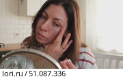 Attractive brunette mid adult woman putting on makeup looking in the mirror. Beautiful lady caring her face. 40 years old female applied cosmetics. Natural beauty and aging concept. Skin care, make-up. Стоковое видео, видеограф Марина Демидюк / Фотобанк Лори