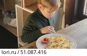Child Eating French Fries with Tomato Sauce in Restaurant Indoors. Little Kid with Blond Hair Enjoy Unhealthy Fast Food. lunch. Caucasian Boy Eats Potato Chips at the Table. Three or Six Years Old. Стоковое видео, видеограф Марина Демидюк / Фотобанк Лори
