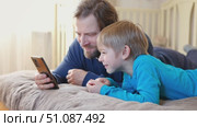 Father and son little boy laughing and using phone. They watching funny videos together, playing games on smartphone. Concept technology, smartphone addicted. Fun weekend activity. Modern fatherhood. Стоковое видео, видеограф Марина Демидюк / Фотобанк Лори