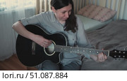 Woman Practicing Guitar in Cozy Room at Home. Strumming black acoustic guitar. Female learning to play music. Person hand on a guitar neck. Guitarist working on melody, performance, practice indoors. Стоковое видео, видеограф Марина Демидюк / Фотобанк Лори