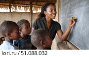 A teacher in Africa facilitating a discussion with students about science, a chalkboard with diagrams in the background. Black African children from disadvantaged families study in school, read books, receive primary education, volunteer service. Стоковое AI-изображение, AI-художник ALLA YURTAYEVA / Фотобанк Лори