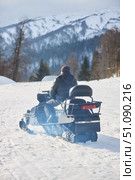 Transport snowmobile with driver on the background of white snow and high mountains. Winter travel in mountainous and forested areas. Стоковое фото, фотограф Наталия Кирсанова / Фотобанк Лори