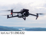 DJI Mavic 3 pro quadcopter on a cloudy sky background . Drone captures stunning aerial view of mountain landscape while flying over lush valleys and misty peaks during golden hour. Редакционное фото, фотограф Владимир Разгуляев / Фотобанк Лори