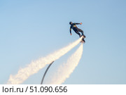 Flyboard enthusiast soars high above the water, propelled by powerful jets of water shooting from the board. The stunning backdrop features a clear blue sky, enhancing excitement of this water sport. Стоковое фото, фотограф Владимир Разгуляев / Фотобанк Лори