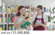 Female shopper scans QR code on label of detegrent using her smartphone. Young sales girl helps to choose a detergent in supermarket. Стоковое видео, видеограф Яков Филимонов / Фотобанк Лори