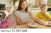 Children siblings painting Easter egg sitting together at table. Easter Family traditions. Teen girl teaching happy little brother and sister to dye, decorate eggs with paints. Preparation to holidays. Стоковое видео, видеограф Марина Демидюк / Фотобанк Лори
