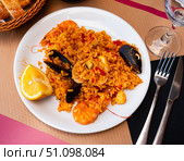 Paella made of rice and different seafood served in plate with table appointments. Стоковое фото, фотограф Яков Филимонов / Фотобанк Лори