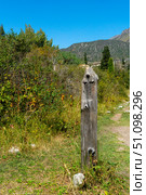 Wooden milepost with carved hiker icon beside dirt track, Ala-Archa National Park, Kyrgyzstan. Subalpine, distant crags. Route for walkers, climbers, backpackers, summit ascents, day outings. Стоковое фото, фотограф Андрей Ка / Фотобанк Лори