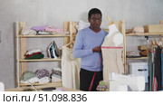 Experienced tailor working in sewing studio, using laptop for video call while adjusting linen dress on mannequin and discussing fit or design details remotely. Стоковое видео, видеограф Яков Филимонов / Фотобанк Лори