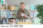 Interested senior male customer scanning QR code on pills packaging with phone to read usage instructions, reviews, or learn about correct dosage before buying in drugstore. Стоковое видео, видеограф Яков Филимонов / Фотобанк Лори