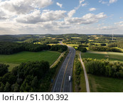 Trucks driving on German autobahn a9 near pegnitz in Bavaria, surrounded by green fields and wind turbines. Стоковое фото, фотограф Данил Руденко / Фотобанк Лори