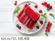 Berry juice popsicles in a plate on a white wooden table with fresh berries. Bright Ice pops with mint leaves and raspberries. Gut-health red pink berry popsicles. Inviting summer scene. Frozen treats. Стоковое AI-изображение, AI-художник Марина Демидюк / Фотобанк Лори