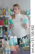 Casual young pregnant woman in white sweater and jeans thoughtfully examining shampoo bottles in personal care store, reading product labels while deciding on best option. Стоковое видео, видеограф Яков Филимонов / Фотобанк Лори