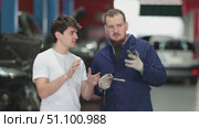 Guy discusses further repairs to his car with car mechanic at a car service center. Стоковое видео, видеограф Яков Филимонов / Фотобанк Лори