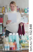 Young pregnant saleswoman in store smiling joyfully while holding work uniform and document, celebrating last working day before maternity leave. Стоковое видео, видеограф Яков Филимонов / Фотобанк Лори