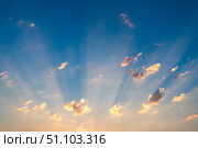 Golden sunbeams are radiating through scattered clouds, creating a mesmerizing spectacle in the vast expanse of the twilight sky during a breathtaking sunset. Стоковое фото, фотограф Ольга Ильина / Фотобанк Лори