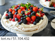 Delicious meringue cake decorated with fresh berries and mint leaves. Стоковое AI-изображение, AI-художник Иван Рябоконь / Фотобанк Лори