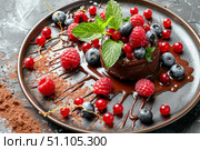 Chocolate fondant cake decorated with fresh berries and mint leaves on elegant plate. Стоковое AI-изображение, AI-художник Иван Рябоконь / Фотобанк Лори
