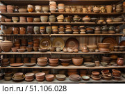 Displaying earthenware crockery, wooden shelves full of handmade pottery. Стоковое AI-изображение, AI-художник Иван Рябоконь / Фотобанк Лори