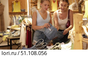 Two women choosing trousers in clothing store. Стоковое видео, видеограф Яков Филимонов / Фотобанк Лори