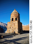 Stepantsminda, Georgia - January 03, 2023: Gergeti Church of the 14th century at the foot of Mount Kazbek. Редакционное фото, фотограф Наталия Кирсанова / Фотобанк Лори