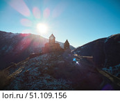 Stepantsminda, Georgia - January 03, 2023: Gergeti Church of the 14th century at the foot of Mount Kazbek. Редакционное фото, фотограф Наталия Кирсанова / Фотобанк Лори