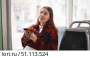Woman sits in a tram and calls friends on the phone. Girl uses public transport to get to the meeting point. Стоковое видео, видеограф Яков Филимонов / Фотобанк Лори