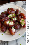 Cream cheese stuffed dates arranged on a plate with herbs. Стоковое AI-изображение, AI-художник DeFusum / Фотобанк Лори