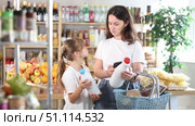 Checking expiration date of milk - mother and daughter checking qr code on a bottle of milk. Стоковое видео, видеограф Яков Филимонов / Фотобанк Лори