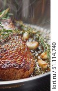 Close up of steak searing in stainless steel frying pan, fresh rosemary and thyme sprigs, whole garlic cloves. Стоковое AI-видео, аниматор Татьяна  Бральнина / Фотобанк Лори