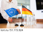 Little flag of Germany on table and flag of European Union put next to it by young woman. Стоковое фото, фотограф Яков Филимонов / Фотобанк Лори