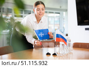 Young lady sets miniatures flags of Russia and NATO before international negotiations. Стоковое фото, фотограф Яков Филимонов / Фотобанк Лори