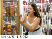 Interested young woman viewing copper utensil placed on display case. Стоковое фото, фотограф Яков Филимонов / Фотобанк Лори