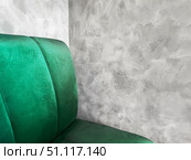 Elegant green velvet chair or sofa positioned against a textured gray wall, modern interior design elements and creating a stylish atmosphere for contemporary spaces, copy space. Стоковое фото, фотограф Елена Гоосен / Фотобанк Лори